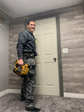 Daniel Brown standing in front of a door holding a power tool. 