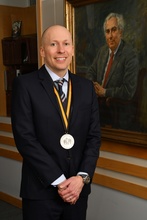 Professor Yockey stands in front of the portrait of David H. Vernon after his investiture celebration